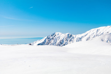 Fototapeta na wymiar The japan alps or the snow mountains wall of Tateyama Kurobe alpine in sunshine day with blue sky background is one of the most important and popular natural place in Toyama Prefecture, Japan.