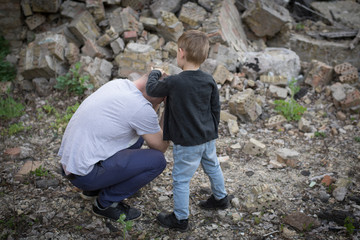father and son among the ruins of a destroyed building