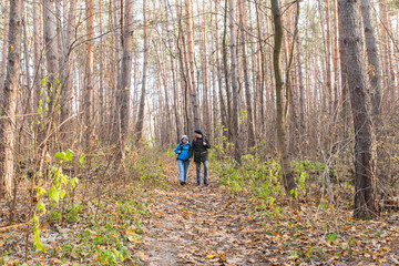 Obraz premium adventure, travel, tourism, hike and people concept - smiling couple walking with backpacks over autumn natural background