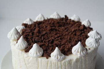 white cake with chocolate chip on top and meringue on top on a light background