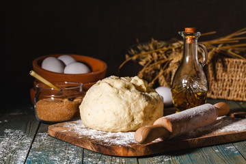 Ingredients for baking croissants - flour, wooden spoon, rolling pin, eggs, egg yolks, butter served on wooden background