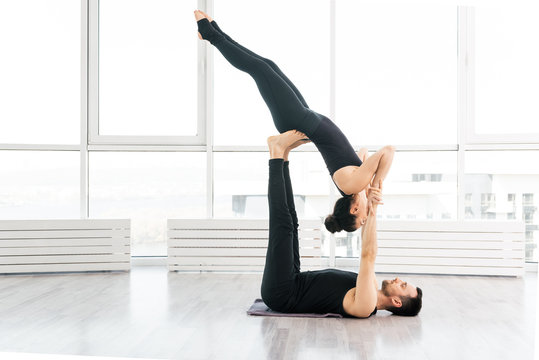 Positive woman practice acro yoga with man partner at studio
