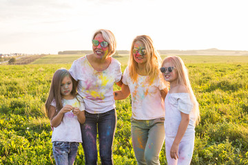 Festival of holi, friendship, happiness and holidays concept - little girls and women in glasses hugging on the festival of Holi.