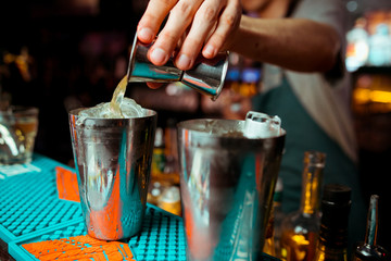 Bartender is adding ingredient in shaker at bar counter