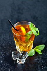 Traditional fresh iced tea with lemon, mint leaves and ice cubes in glass.