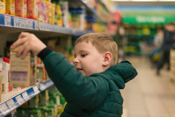 Little boy chooses goods in the supermarket.