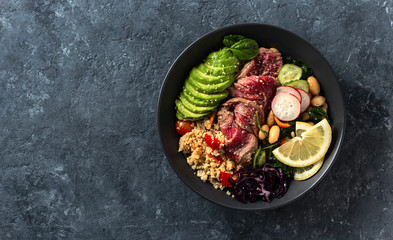 Healthy food buddha bowl with beef steak, beans, couscous, avocado and vegetables on dark background with copy space - Powered by Adobe