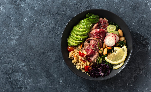 Healthy Food Buddha Bowl With Beef Steak, Beans, Couscous, Avocado And Vegetables On Dark Background With Copy Space