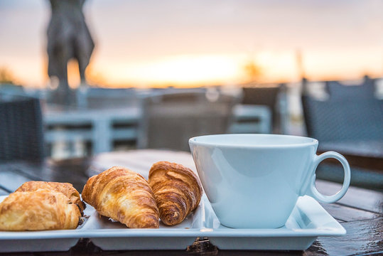 Breakfast with croissants on the sea beach terrace and sunrise