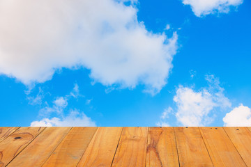 Old Wooden table with blue sky white cloud background.