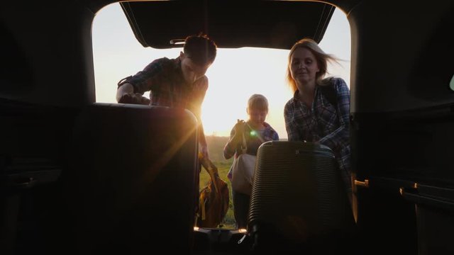 The family with the child is going on a trip, Together they put the bags in the trunk of the car