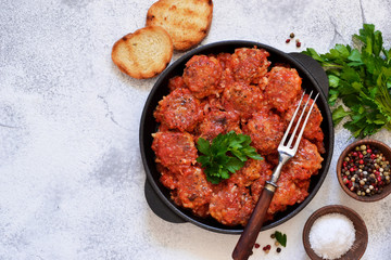 Meatballs with tomato sauce and spices in a pan on the kitchen table. Top view.