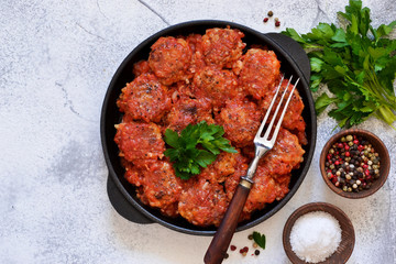 Meatballs with tomato sauce and spices in a pan on the kitchen table. Top view.
