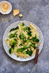 Italian pasta with spinach, broccoli and green peas on a concrete background. Dinner time. Top view.