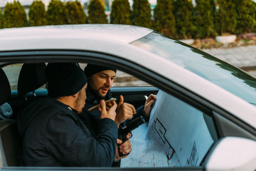 Two Thieves parked in an ally waiting while talking on the phone, observing their target and...