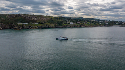 Fototapeta na wymiar Tour boat sets out along the Irish coastline of Howth village