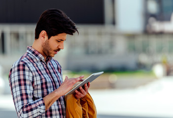 Fashionable businessman using PC tablet outdoors