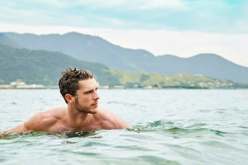 Young dude swimming in sea, looking away