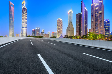 Obraz premium Shanghai modern commercial office buildings and empty asphalt road at night,panoramic view