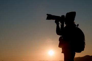 The photographer's silhouette with his camera on a sunset