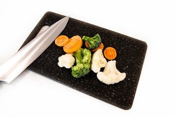 Bukiet mrożonych warzyw na desce z nożem