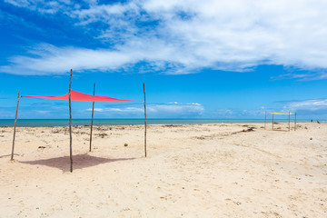 Beautiful beach view with a pink tent on sunny summer day and sea and blue sky in the background. Concept of vacations, peace and relaxation. Ponta do Corumbau, Bahia, Brazil.