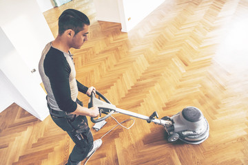 Einölen von Eichenparkett, Arbeiter mit poliermaschine und Werkzeug.