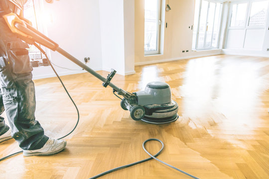 Ein&ouml;len von Eichenparkett, Arbeiter mit poliermaschine und Werkzeug.