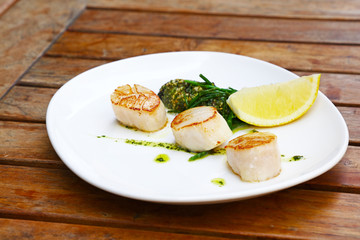 Portion of grilled scallops on plate on table