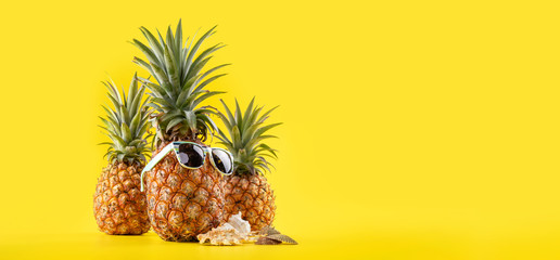 Creative pineapple looking up with sunglasses and shell isolated on yellow background, summer...