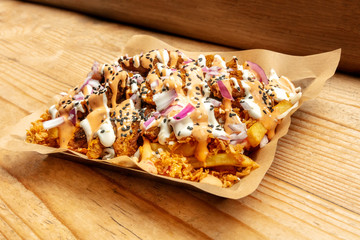 A photo of an appetizing vegan dish with fried potatoes, onions, vegan cheese and soy meat on a rustic wooden background with a place for text