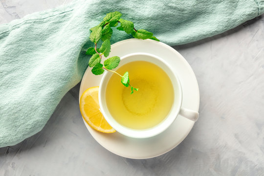 A photo of a cup of green tea with lemon and mint leaves, shot from above with copy space