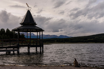 A gnome sat in front  of the lake against a pier and Andes mountains