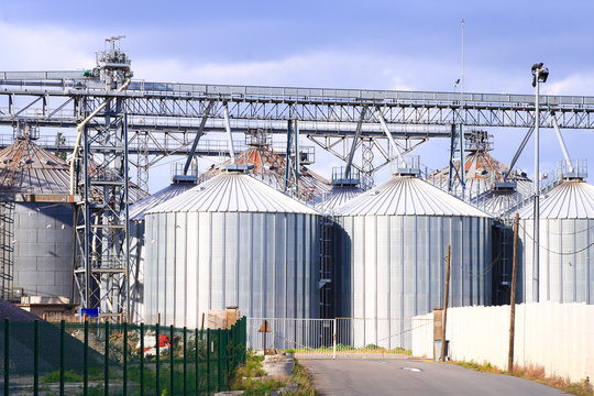 Set of metal tanks aligned under structures and gangway. View of the fuel or water tanks of a factory and barrier for protection
