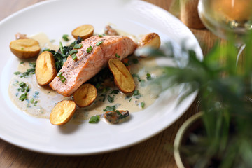 Baked salmon fillet with baked potatoes on a cream sauce with chives