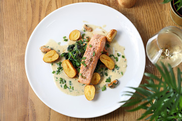 Grilling salmon fillet with baked potatoes on a cream sauce with chives