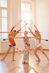 Team of little girls practicing rhythmic gymnastics with clubs, copy space