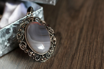 Oval pendant with grey natural stone on wooden background