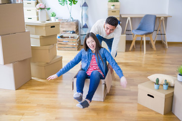Funny asian couple having fun, riding inside cardboard box smiling happy, very excited moving to a new house
