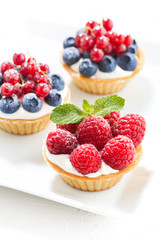 mini cakes with cream and berries, top view vertical