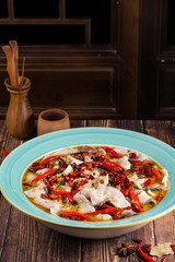 Fish in sour soup with chilli in a blue ceramic dish