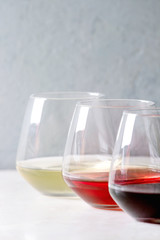 Variety of wine. Red, rose and white wine in old fashion glasses in row on white marble table. Copy space