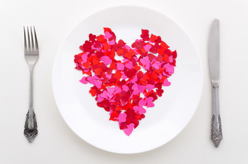 Top view red heart shape on a white plate with silverware. Background for a restaurant banner. Dinner on valentines day concept
