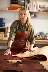 Waist up portrait of female tanner working with leather in workshop, copy space