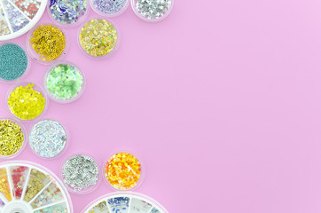 Top view sequins for nails in a jars. Sparkles in a jar. Pink background with copy space