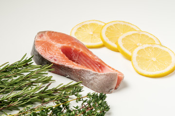 Steak of red fish, salmon with lemon, rosemary and thyme. Trout on white background.