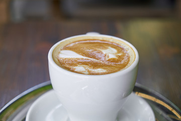 Cup of hot coffee latte on a wooden table