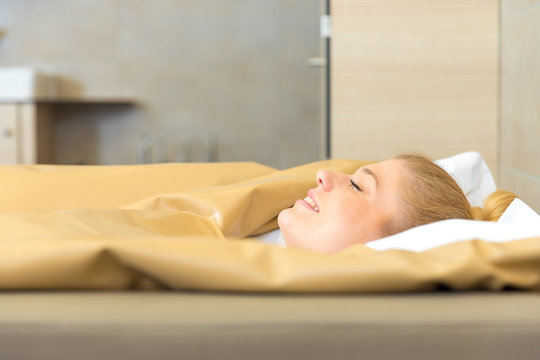 young beautiful woman are doing a fango therapie in a wellness area. friends are on the side of the water bed