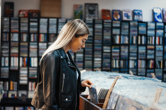 Young attractive woman choosing vinyl record in music record shop.