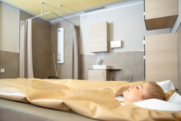 young beautiful woman are doing a fango therapie in a wellness area. friends are on the side of the water bed